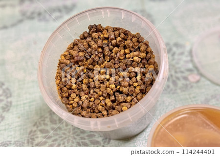 A lot of bee perga as called ambrosia, bee pollen in a plastic container. Top view. Healthy eating. The energy of life. Close-up 114244401