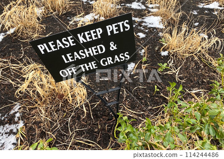 Melting snow on the ground, into which a sign has been stuck prohibiting dogs from walking on the lawn Melting snow on the ground, into which a sign has been stuck prohibiting dogs from walking on the lawn 114244486