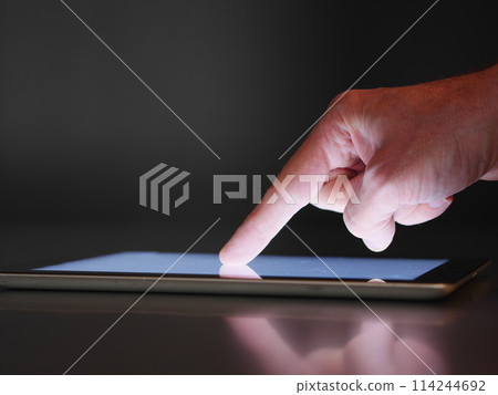 A hand pointing at a tablet screen 114244692