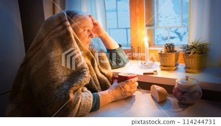 Woman warming herself by a candle in blackout Woman warming herself by a candle in blackout 114244731