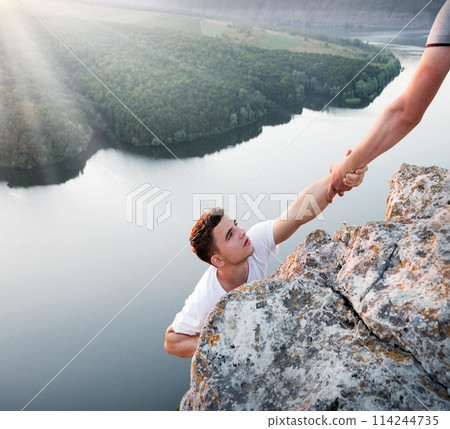 Man help his friend to climb on the rock 114244735