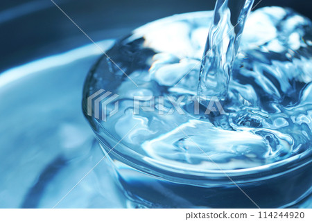Water falling vigorously into a glass 114244920