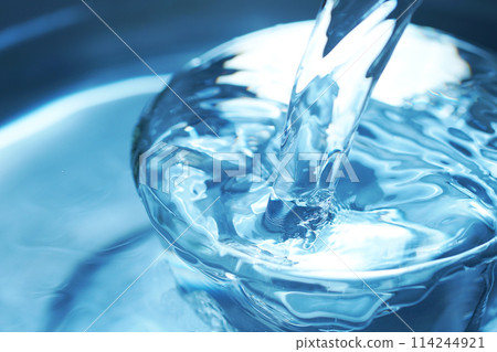 Water falling vigorously into a glass 114244921