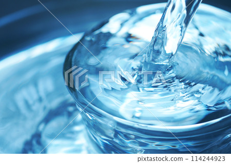 Water falling vigorously into a glass 114244923