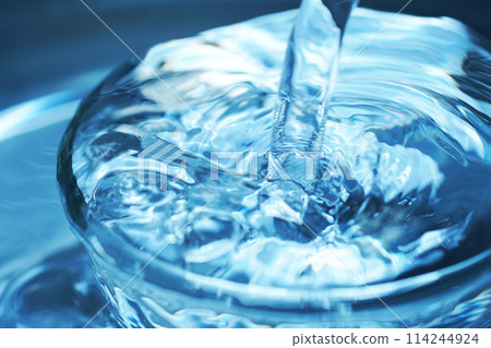 Water falling vigorously into a glass 114244924