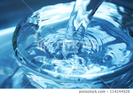 Water falling vigorously into a glass 114244926