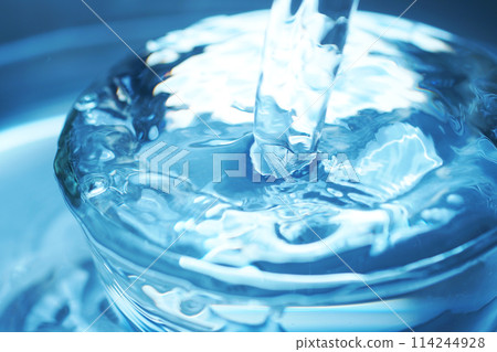 Water falling vigorously into a glass 114244928