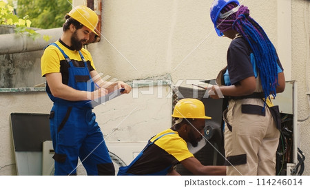 Professionals commissioned for HVAC system annual cleaning, using dusting brush to clean clogged air filter restricting airflow, decreasing efficiency and reducing unit ability to cool air effectively 114246014