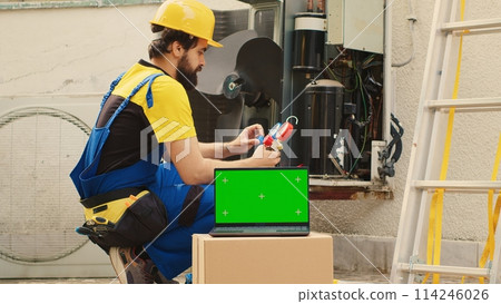 Seasoned mechanic employed by customer to find cause of faulty outdoor hvac system using measurement device, with nitrogen pressure loss over time displayed on chroma key laptop screen Seasoned mechanic employed by customer to find cause of faulty outdoor hvac system using measurement device, with nitrogen pressure loss over time displayed on chroma key laptop screen 114246026