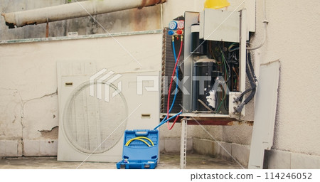 Handheld camera shot of damaged air cooling unit in need of fixing, with malfunctioning electric internal parts and wiring. Outside opened HVAC system not working anymore, ready to be repaired 114246052