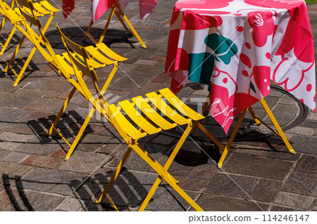 Yellow chairs and a table with a red patterned tablecloth 114246147