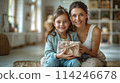 Happy Mother and Daughter Sharing a Gift at Home, ai-generated item 114246678