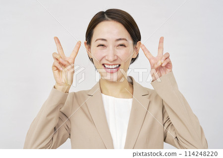 Middle-aged businesswoman making a peace sign with both hands on a white background 114248220