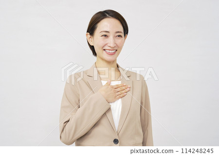Portrait of a middle-aged businesswoman with her hand on her chest, white background 114248245