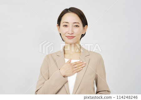 Portrait of a middle-aged businesswoman with her hand on her chest, white background, looking at the camera 114248246