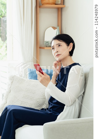 A woman using a smartphone in the living room 114248979
