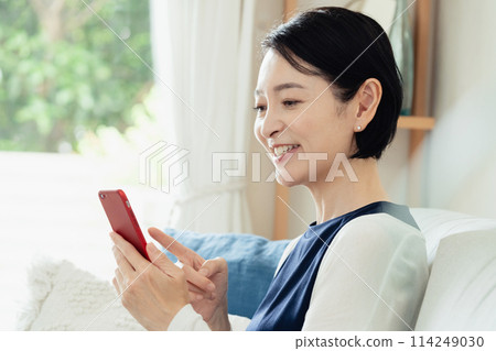 A middle-aged woman operating a smartphone 114249030