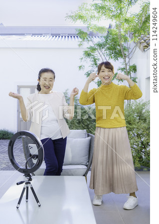 Senior and middle-aged women streaming videos on TikTok, vertical position 114249604