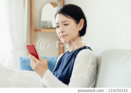 使用智能手機的婦女在客廳 114250142
