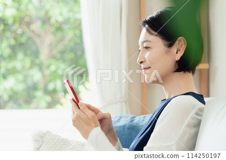 操作智慧型手機的中年婦女 114250197