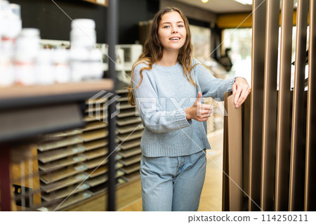 Female customer holding wooden panels samples in hardware store 114250211