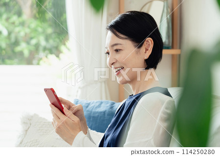 A middle-aged woman operating a smartphone A middle-aged woman operating a smartphone 114250280