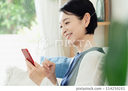 A middle-aged woman operating a smartphone A middle-aged woman operating a smartphone 114250281
