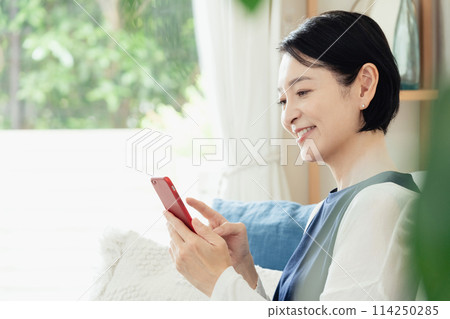 A middle-aged woman operating a smartphone 114250285