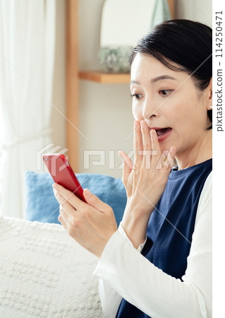 A woman using a smartphone in the living room 114250471