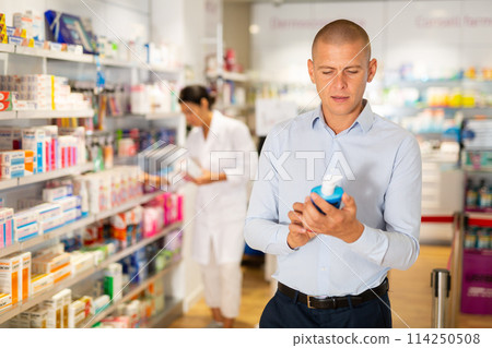 Male customer looking for products of body care in pharmacy closeup Male customer looking for products of body care in pharmacy closeup 114250508