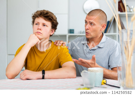 Teenager feeling upset and his father comforting him Teenager feeling upset and his father comforting him 114250582