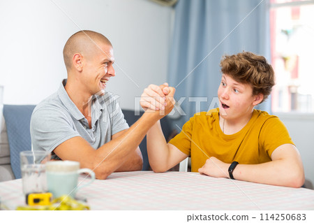 Son and his dad arm wrestling 114250683