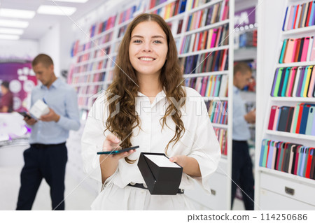 Happy girl chooses mobile phone in store 114250686