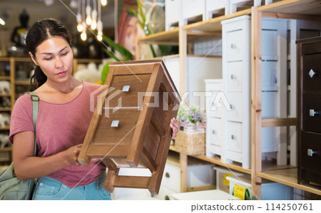 Woman choosing bedside table in store 114250761