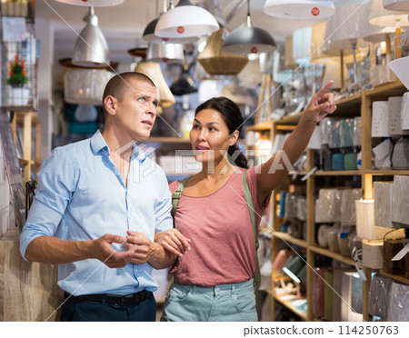 Man and woman choosing lamps in store Man and woman choosing lamps in store 114250763