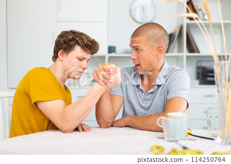 Father and son competing in arm wrestling Father and son competing in arm wrestling 114250764