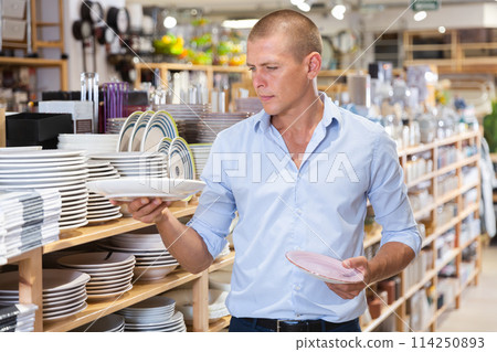 Man choosing plates in store 114250893