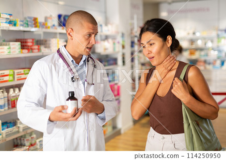 Woman complains to a pharmacist about a sore throat. Help in choosing a medicine in pharmacy 114250950