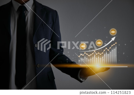 Businessman Hold Tablet and 2023 Stock Market Bar Chart or Graph Trend 114251823