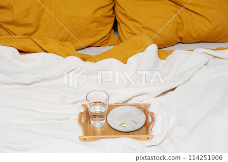 Glass of water and vitamin capsules placed on the bed. Glass of water and vitamin capsules placed on the bed. 114251906
