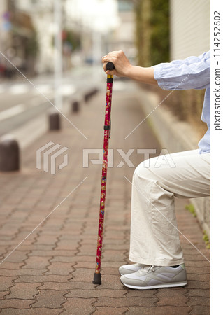 Hands of a middle-aged woman holding a cane 114252802