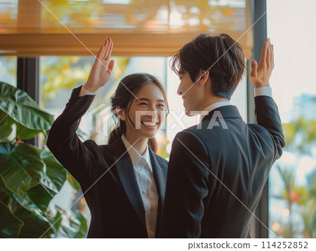 Male and female business people rejoicing at a reunion by high-fiving each other 114252852