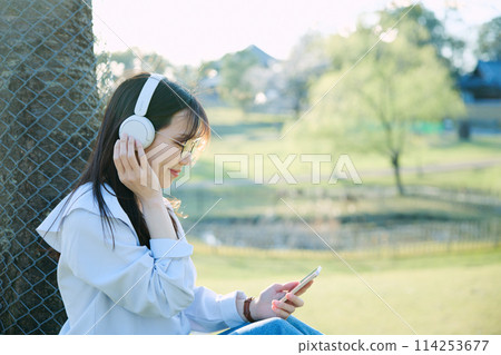 A woman listening to music under the cherry blossoms A woman listening to music under the cherry blossoms 114253677