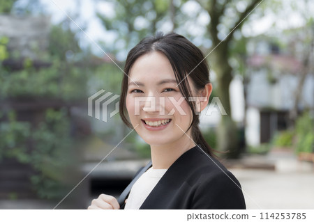 A young woman wearing a suit outdoors, looking at the camera close-up, sales, outside work, image of a young new graduate A young woman wearing a suit outdoors, looking at the camera close-up, sales, outside work, image of a young new graduate 114253785