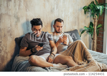 Happy gay couple taking selfie on bed at home 114254431