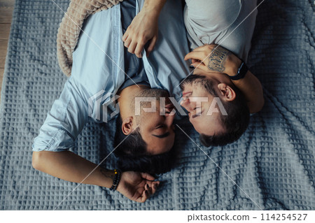 Handsome sleepy man with bristle kissing good night male partner lying in bed Handsome sleepy man with bristle kissing good night male partner lying in bed 114254527