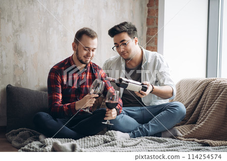 Laughing male gay couple drinking wine and preparing a meal 114254574