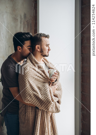 two handsome homosexual guys while standing near window two handsome homosexual guys while standing near window 114254624