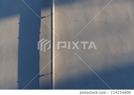 A wall and a pipe in the evening light, the shadow of the pipe on the wall A wall and a pipe in the evening light, the shadow of the pipe on the wall 114254806