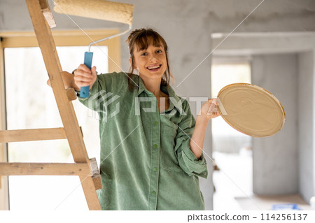 Joyful woman paints walls at home 114256137